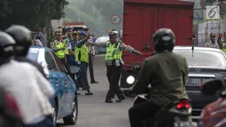 Petugas polisi lalu lintas memberhentikan kendaraan saat pemberlakuan sistem ganjil genap di pintu masuk Gardu Tol Cibubur 2, Jakarta, Senin (16/4). Kebijakan ini diterapkan untuk mengurai kemacetan di ruas Tol Jagorawi. (Liputan6.com/Faizal Fanani)