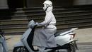Seorang wanita mengendarai sepeda motor sambil menggunakan pakaian pelindung saat melintasi pusat kota Hanoi, Rabu (15/6). Vietnam menghadapi gelombang panas dengan suhu hingga mencapai 40 derajat celcius. (Hoang DINH NAM/AFP)