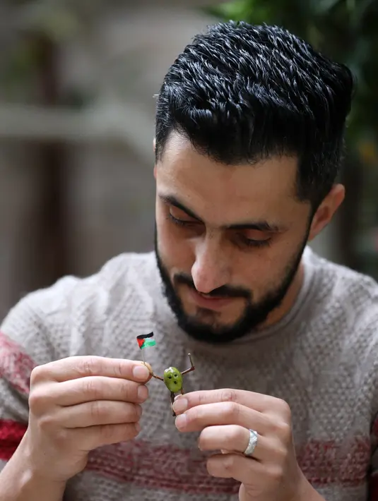 Nidal Asmar (29) membuat orang-orangan dari buah zaitun dan ranting kecil di rumahnya di Desa Roujeeb, Kota Nablus, Tepi Barat, Palestina, 21 November 2020. Asmar membuat karya-karya seni kecil dari buah zaitun untuk meningkatkan kesadaran publik tentang pandemi COVID-19. (Xinhua/Ayman Nobani)