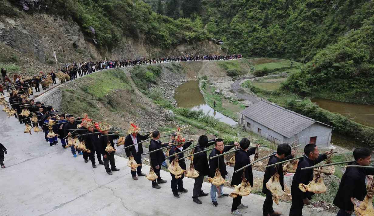 Orang-orang dari etnis minoritas Miao membawa persembahan ketika mereka menghadiri upacara pengorbanan untuk dewa gunung di Jianhe di provinsi Guizhou barat daya China (15/4). (AFP Photo/China Out)