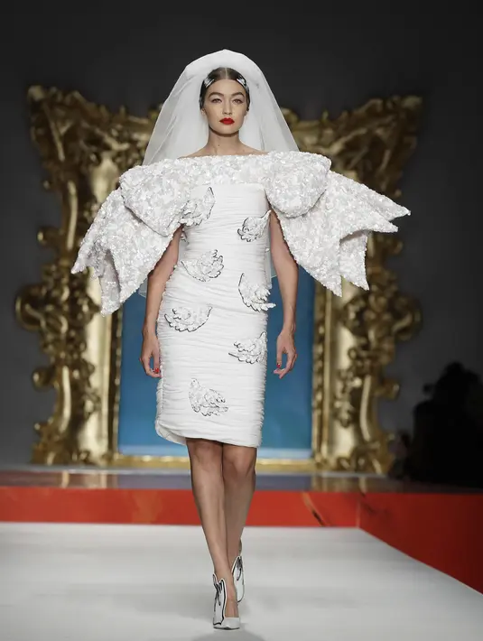 Model Gigi Hadid berjalan di catwalk memakai koleksi Moschino Spring-Summer 2020 selama pekan mode di Milan, Italia (19/9/2019). Gigi tampil anggun dengan sentuhan apik pada balutan gaun pengantin berwarna putih untuk showcase unik yang terinspirasi oleh Alice In Wonderland. (AP Photo/Luca Bruno)