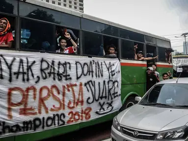 Suporter Persija berada di dalam bus melewati jalan Gatot Subroto menuju stadion Gelora Bung Karno, Jakarta, Minggu (9/12). Antusiasme ribuan suporter Persija bersiap mendukung tim kesayangannya bertanding melawan Mitra Kukar. (Liputan6.com/Faizal Fanani)