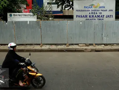 Seorang wanita mengendarai motor melewati depan Pasar Kramatjati yang  mengalami revitalisasi di Jakarta, Jumat (23/10/2015). Pasar Kramatjati mulai direvitalisasi pada Juli lalu dan ditargetkan selesai hingga 18 bulan kedepan. (Liputan6.com/Yoppy renato)