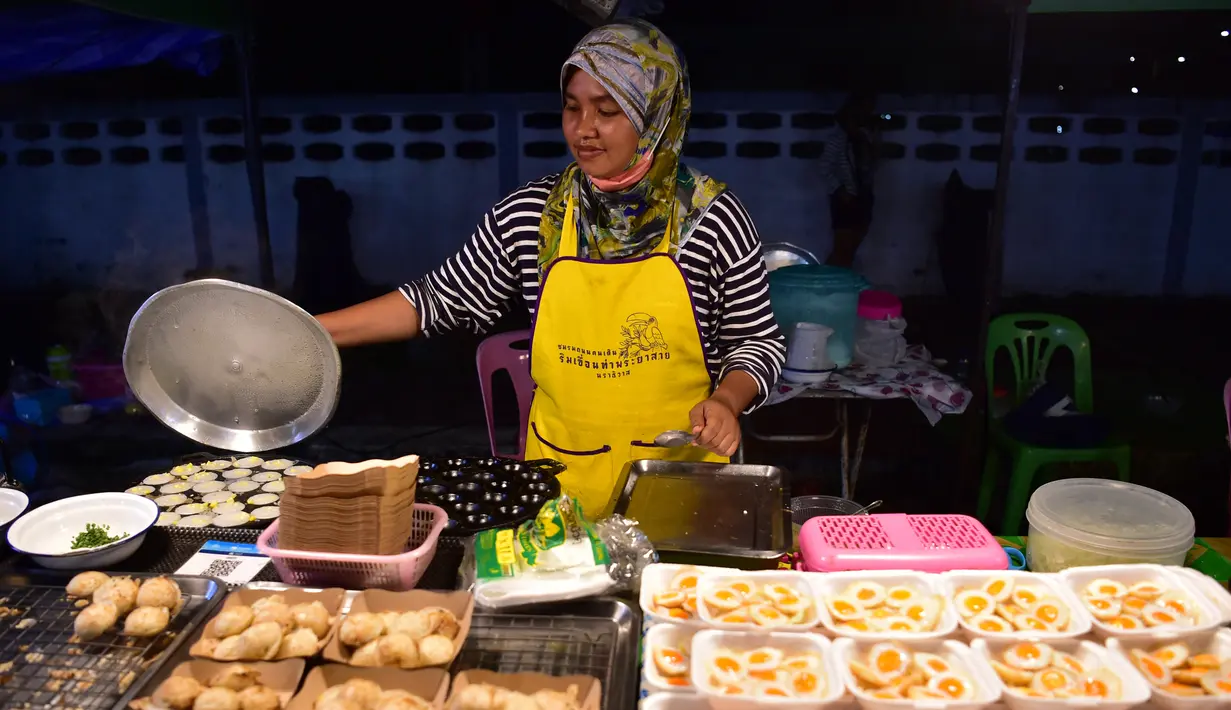 <p>Penjual membuat makanan untuk pembeli  selama bulan suci Ramadhan di pasar malam di provinsi Narathiwat, Thailand selatan (21/4/2022). Penjual makanan jalanan mendirikan kios mereka untuk menjual makanan kepada umat Muslim untuk berbuka puasa. (AFP/Madaree Tohlala)</p>