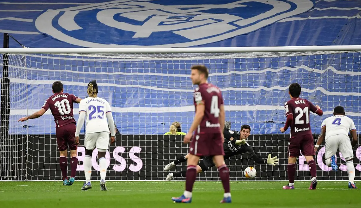 Pemain Real Sociedad Mikel Oyarzabal (kiri) mencetak gol lewat tendangan penalti ke gawang Real Madrid yang dijaga Thibaut Courtois (tengah) pada pertandingan sepak bola Liga Spanyol di Stadion Santiago Bernabeu, Madrid, Spanyol, 5 Maret 2022. Real Madrid menang 4-1. (PIERRE-PHILIPPE MARCOU/AFP)