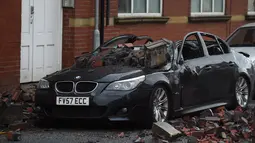 Reruntuhan atap apartemen tampak menimpa sebuah mobil yang diparkir akibat angin kencang yang melanda di Leigh, barat laut Inggris, Rabu (18/11). (AFP PHOTO/Paul Ellis)