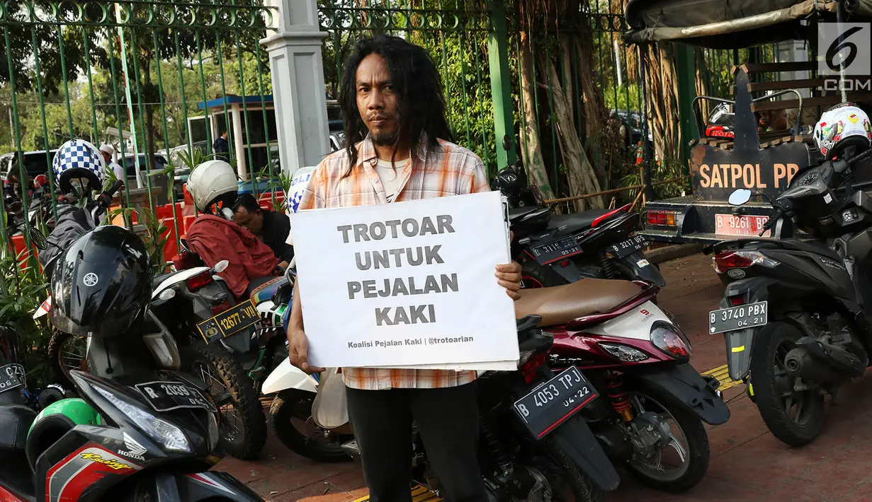 Aktivis Koalisi Pejalan Kaki (KPK) melakukan aksi diantara motor-motor yang terparkir di kawasan Monas, Jakarta, Jumat (28/7). Aksi tersebut dilakukan untuk mengembalikan trotoar sesuai fungsinya. (Liputan6.com/Immanuel Antonius)