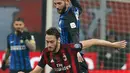 Pemain AC Milan Hakan Calhanoglu berebut bola dengan pemain Inter Milan Roberto Gagliardini saat pertandingan Liga Italia di stadion San Siro, Milan (4/4). (AP Photo / Antonio Calanni)