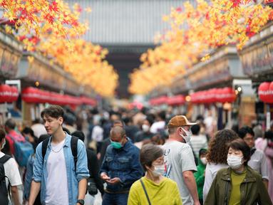 Turis melihat sekeliling saat berjalan di distrik hiburan Asakusa, Tokyo, Jepang, Senin (17/10/2022). Kawasan ini dipenuhi pejalan kaki yang melihat toko-toko suvenir yang mengarah ke kuil Buddha Sensoji yang terkenal di Tokyo. (AP Photo/Hiro Komae)