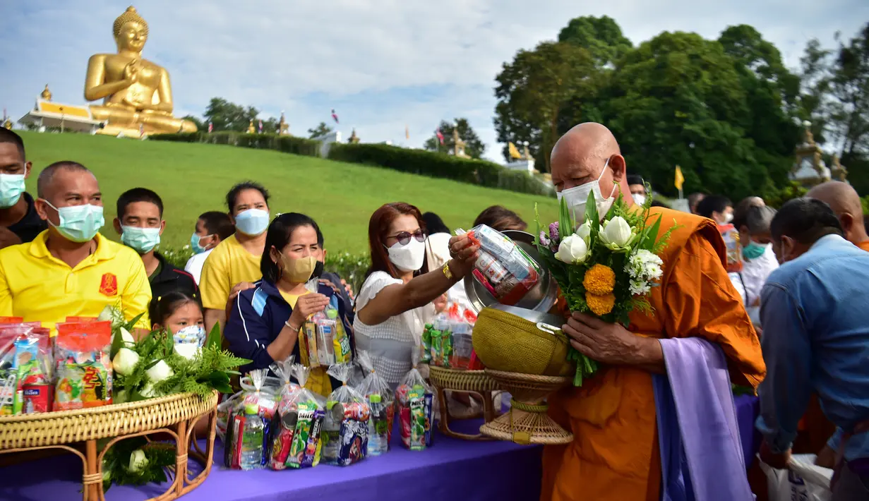 Para biksu Buddha diberi sedekah oleh umat saat mereka memperingati Hari Makha Bucha di kota Narathiwat, Thailand selatan  (6/3/2023). Umat Buddha biasanya pergi ke vihara untuk berbuat kebajikan seperti berderma, bermeditasi, dan mendengarkan dhamma. (AFP/Madaree Tohlala)