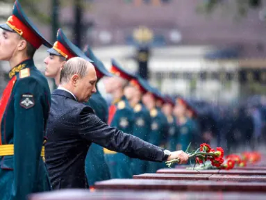 Presiden Rusia, Vladimir Putin meletakkan bunga di tengah hujan lebat saat upacara kehormatan untuk memperingati invasi Nazi Jerman pada 1941 di Benteng Kremlin, Moskow, Kamis (22/6). (Alexei Druzhinin/Sputnik, Kremlin Pool Photo via AP)