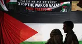Para pengunjuk rasa pro-Palestina berdiri di depan bendera dan spanduk besar dalam unjuk rasa yang diadakan untuk menandai peringatan "Nakba" atau "Malapetaka" tahun 1948, di Sydney pada tanggal 15 Mei 2024. (DAVID GRAY/AFP)