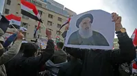 Rakyat Irak membawa foto ulama Syiah top negara itu, Ayatollah Ali al-Sistani, ketika mereka berdemonstrasi di ibu kota Tahrir Square, Baghdad, 5 Desember 2019. (Foto: AFP)