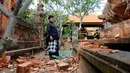 Pemuka agama memantau kerusakan pada bagian candi yang runtuh akibat gempa di Pura Lokanatha, Denpasar, Bali, Selasa (16/7/2019). Gempa Magnitudo 5,8  yang mengguncang Bali tidak menimbulkan korban jiwa, tapi sejumlah bangunan di beberapa kawasan mengalami kerusakan. (AP/Firdia Lisnawati)