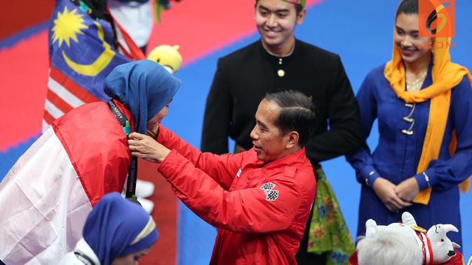 Presiden RI, Joko Widodo, mengalungkan medali kepada atlet taekwondo, Defia Rosmaniar, pada Asian Games 2018 di JCC, Jakarta, Minggu (19/8/2018) (Bola.com/Peksi Cahyo)