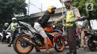 Petugas Kepolisian melakukan razia pengendara motor dengan knalpot bising di kawasan Monumen Nasional (Monas), Jakarta, Minggu (7/3/2021). Razia knalpot bising tersebut guna memberikan kenyamanan bagi warga yang hendak berolahraga di area tersebut. (Liputan6.com/Herman Zakharia)