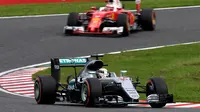 Pebalap Mercedes, Lewis Hamilton, mengungguli pebalap Ferrari, Sebastian Vettel, dalam balapan F1 GP Jepang di Sirkuit Suzuka, Jepang, Minggu (9/10/2016). (AFP/Toshifumi Kitamura)