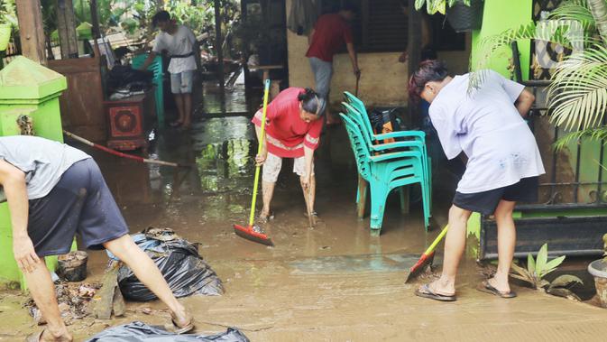 Warga membersihkan lumpur sisa banjir di halaman rumahnya di perumahan Ciledug Indah, Tangerang Senin (22/2/2021). Banjir yang menggenangi perumahan tersebut membuat warga mengalami kerugian cukup besar karena barang-barang berharga mereka rusak parah. (Liputan6.com/Angga Yuniar)