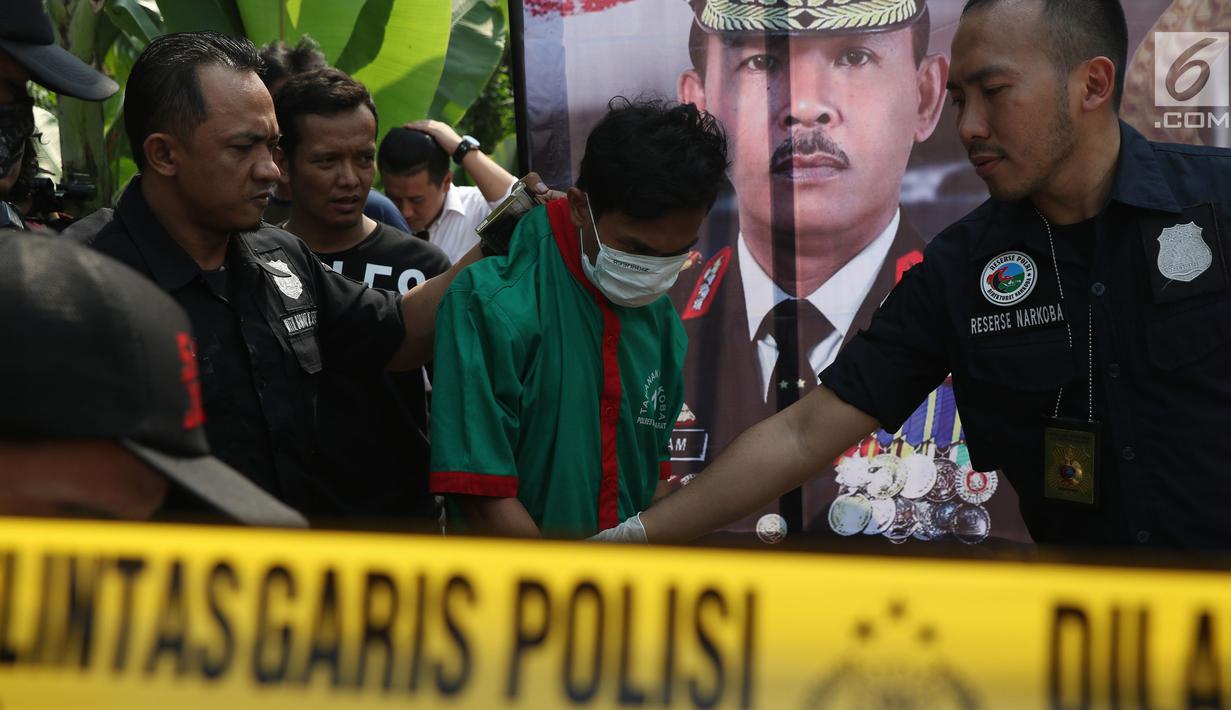 Petugas menggiring salah satu dari tiga tersangka pengedar dan pembuat narkoba di sebuah perumahan di Kawasan Pondok Rajeg, Cibinong, Jawa Barat, Senin (24/9). Polisi juga menahan sejumlah barang bukti terkait. (Liputan6.com/Helmi Fithriansyah)