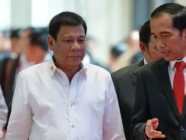 Presiden Filipina Rodrigo Duterte (kiri) mendengarkan Presiden Indonesia Joko Widodo saat menuju sidang paripurna KTT ASEAN di Vientiane (6/9). (AFP PHOTO/Roslan Rahman)