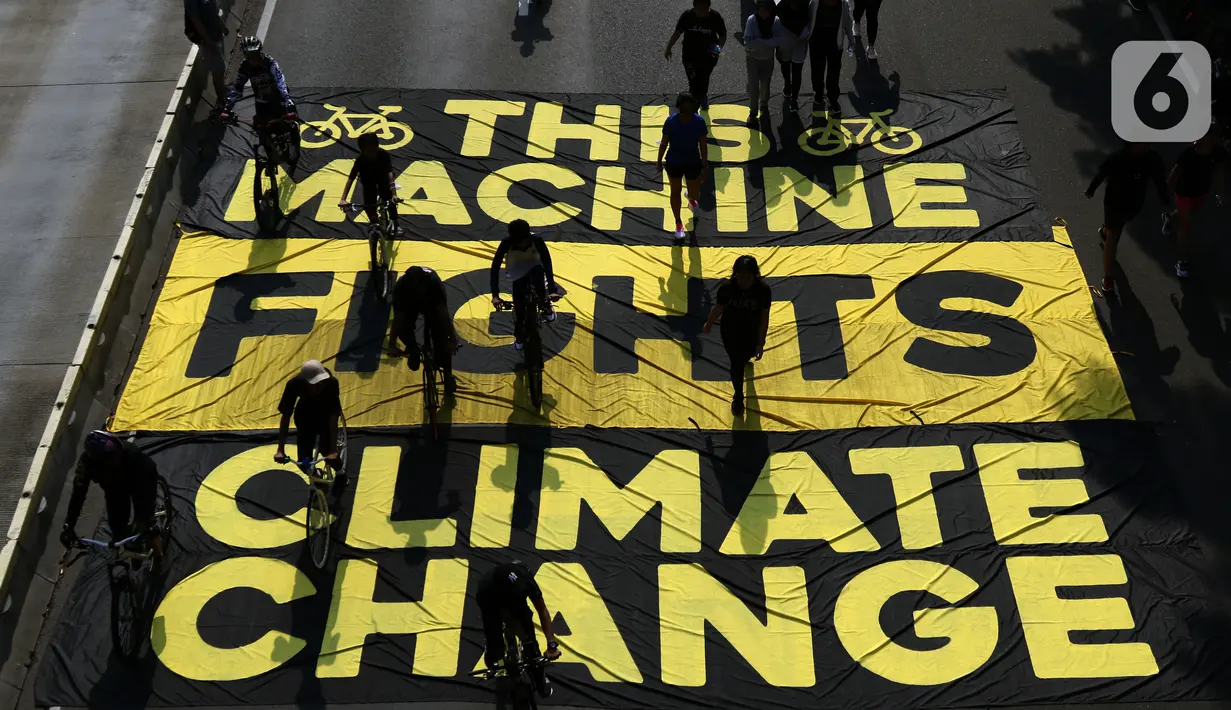 Pesepeda melintas di atas banner yang dibentangkan aktivis Greenpeace dan Bike2Work di Jalan Jenderal Sudirman, Jakarta, Minggu (5/6/2022). Aksi untuk mengkampanyekan penggunaan sepeda sebagai kendaraan ramah lingkungan dan solusi pembangunan Jakarta Kota Ramah Pesepeda. (Liputan6.com/Helmi Fithriansyah)