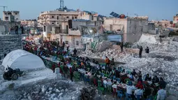 Di tengah gundukan puing dan reruntuhan bangunan yang hancur akibat gempa magnitudo 7,8, warga menikmati hidangan buka puasa Ramadhan bersama. (AFP/Aaref Watad)