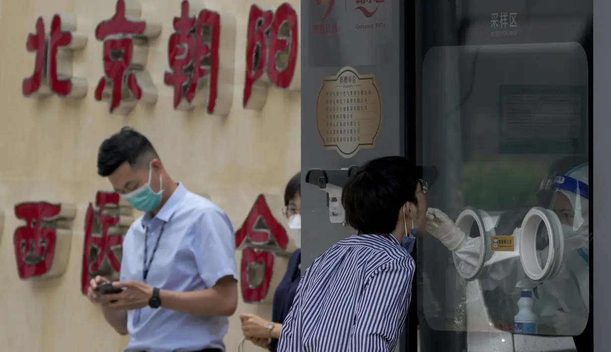 <p>Seorang pekerja menjalani tes swab tenggorokan di fasilitas pengujian COVID-19 di Beijing, Senin (13/6/2022). Pejabat kesehatan kota mengatakan sejauh ini ada 166 kasus yang dikonfirmasi terkait dengan wabah yang dimulai di bar Heaven Supermarket di daerah Sanlitun pada Kamis, 9 Juni 2022. (AP Photo/Andy Wong)</p>