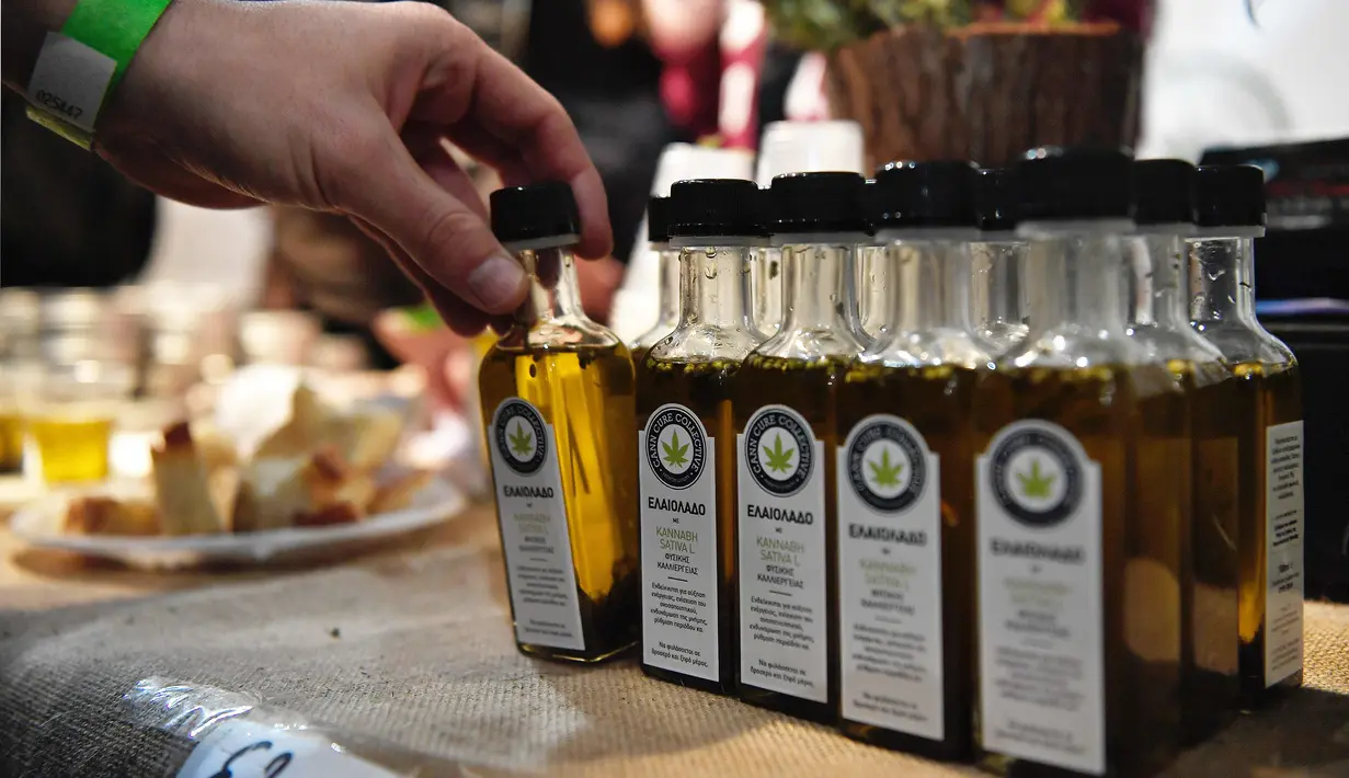 Pengunjung mencoba minyak zaitun dari ganja di International Cannabis Expo yang berlangsung di Athena, Yunani, Minggu (14/1). Perusahaan Yunani, Israel, dan Kanada mengungkapkan minatnya dalam investasi ganja medis di Yunani. (AFP PHOTO/LOUISA GOULIAMAKI)