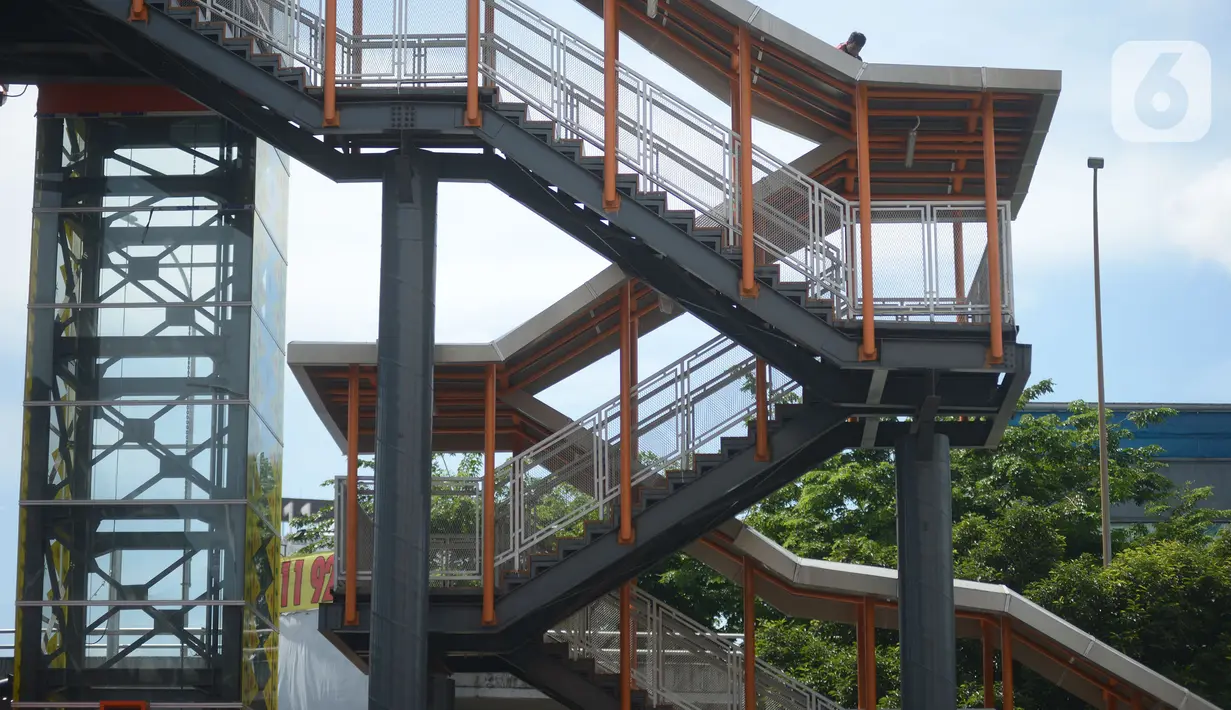 Pekerja terlihat di atas atap jembatan penyeberangan orang (skywalk) yang menghubungkan Stasiun Kebayoran dengan Halte Transjakarta di Kebayoran Lama, Jakarta, Jumat (6/1/2023). Skywalk sepanjang 450 meter tersebut untuk memudahkan mobilitas penumpang Transjakarta atau KRL yang beralih moda transportasi. (merdeka.com/Imam Buhori)
