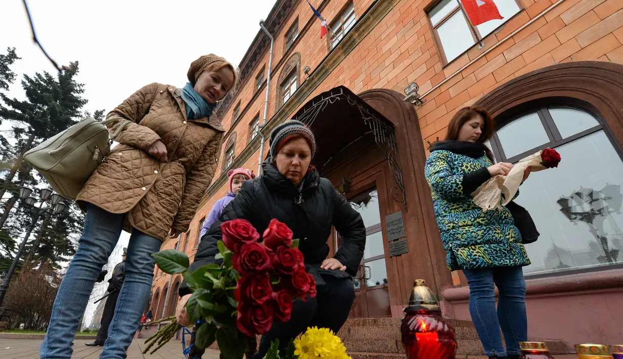 Seorang wanita menaruh bunga di depan Kedutaan Besar Prancis di Minsk Sabtu (14/11/2015) . Karangan bunga tersebut untuk menghormati para korban serangan mematikan di Paris. (AFP Photo/Maxim Malinovsky)