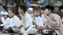 Sejumlah anak berbincang saat mendengarkan khotbah usai melaksanakan salat Idul Fitri 1438 H di kawasan Jatinegara, Jakarta, Minggu (25/7). Ruas Jalan Jatinegara Barat disulap menjadi tempat pelaksanaan salat Ied. (Liputan6.com/Yoppy Renato)