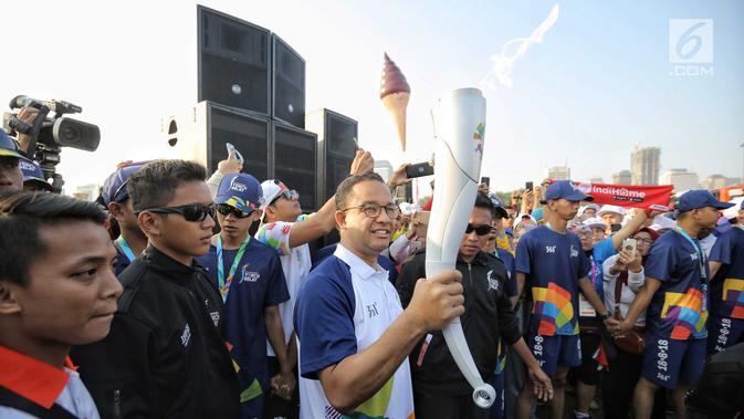 Gubernur DKI Jakarta Anies Baswedan membawa obor Asian Games 2018 di Jakarta, Sabtu (18/8). Setelah oleh Anies, obor kemudian dibawa lari secara estafet oleh pejabat-pejabat lain. (Liputan6.com/Faizal Fanani)