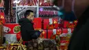 Untuk diketahui, perayaan Tahun Baru Imlek 2577 Kongzili jatuh pada Selasa 17 Februari 2026. Tampak dalam foto, seorang pedagang menikmati makanannya di lapaknya sementara orang-orang berbelanja saat bazar menyambut Tahun Baru Imlek di Beijing, China, Minggu 1 Februari 2026. (AP Photo/Andy Wong)