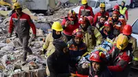 Tim penyelamat mengevakuasi seorang gadis Suriah berusia 12 tahun, Cudi, dari puing-puing bangunan yang hancur di Hatay, Turki, setelah gempa berkekuatan 7,8 melanda tenggara negara itu, Minggu (12/2/2023). Tim penolong mulai kelelahan mencari korban selamat di puing-puing akinbat gempa Turki dan Suriah, ketika korban tewas sudah mencapai 28.000 dan tampaknya akan terus bertambah. (Photo by Yasin AKGUL / AFP)