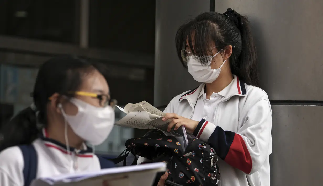 Siswa yang mengenakan masker memeriksa kertas di luar sekolah sebelum hari pertama ujian masuk perguruan tinggi nasional China, atau dikenal gaokao, di Beijing, Selasa (7/6/2022). Lebih dari 11 juta siswa sekolah menengah di seluruh China akan mengikuti ujian masuk perguruan tinggi tahunan setelah negara itu baru saja mengatasi wabah COVID-19 yang parah di Shanghai dan Beijing (AP Photo/Andy Wong)