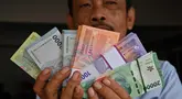 Seorang pria menunjukkan uang kertas Rupiah yang baru, yang akan diberikan kepada anggota keluarganya saat perayaan Idul Fitri, di Jakarta pada 28 Maret 2024. (Adek BERRY/AFP)