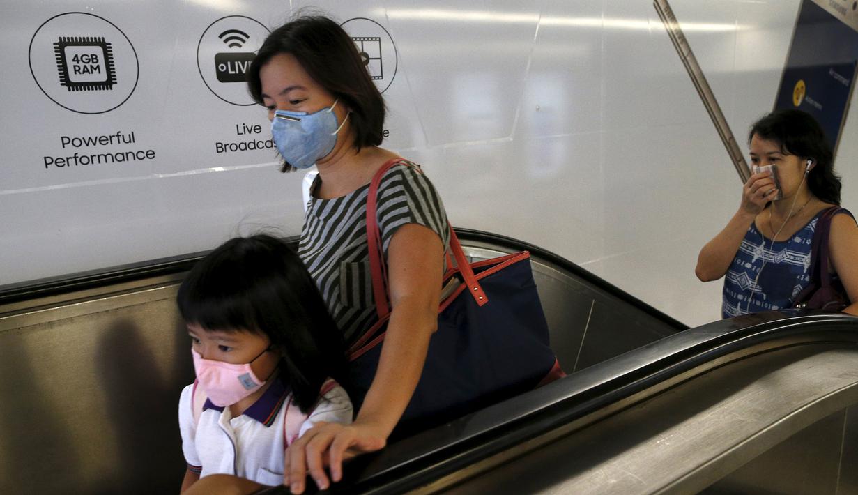 Sejumlah warga memakai masker meninggalkan stasiun kereta api, Singapura (25/9/2015). Sejak Rabu Kualitas udara di Singapura mulai memburuk akibat kabut asap tebal dari wilayah Indonesia. (REUTERS/Edgar Su)  
