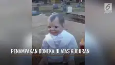 Sebuah boneka berwajah menyeramkan berada di atas kuburan.