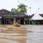 Seorang anak laki-laki menggunakan kotak untuk mengarungi banjir setelah banjir di Serang, Provinsi Banten (1/3/2022).  Berdasarkan data sementara dari Polres Serang Kota, ada 20 titik banjir yang merendam pemukiman warga di Kota Serang. (AFP/Dziki Oktomauliyadi)
