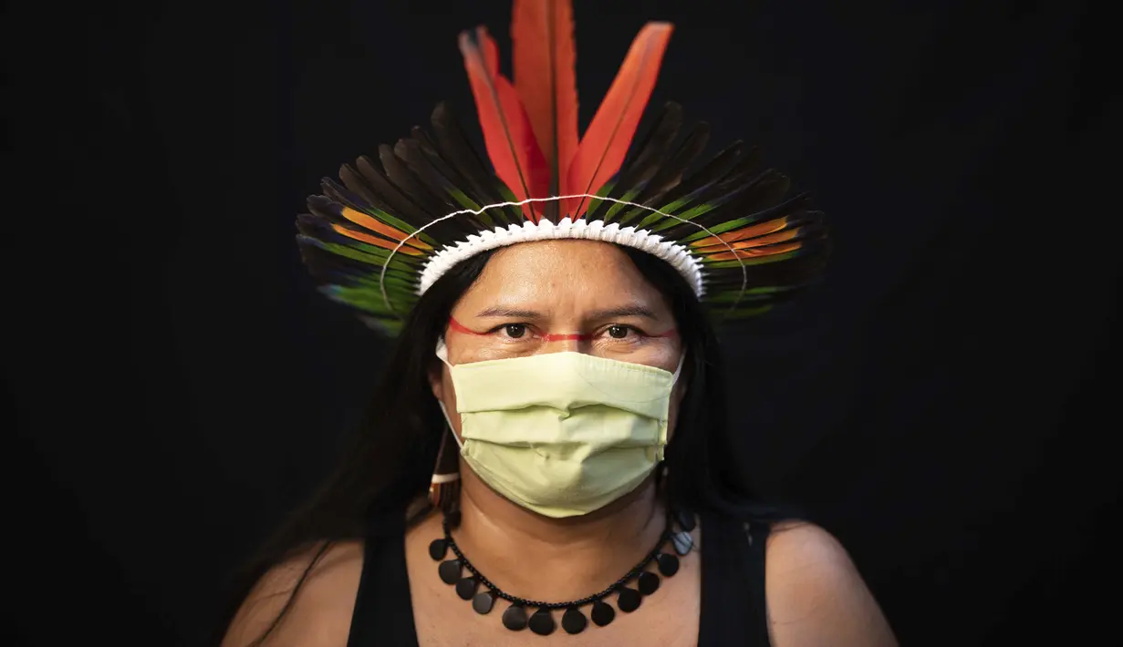 Dilza (39) dari kelompok etnis pribumi Sateré Mawé mengenakan pakaian tradisional sukunya dan masker saat pandemi virus corona COVID-19 di Manaus, Brasil, Rabu (27/5/2020). (AP Photo/Felipe Dana)