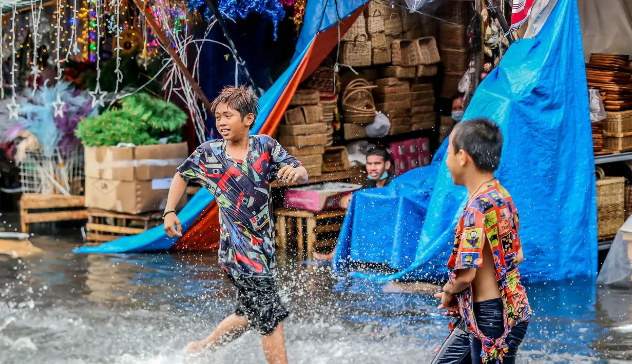 Anak-anak bermain di tengah banjir usai hujan deras yang tiba-tiba mengguyur di sebuah pasar dekorasi Natal di Manila, Filipina (9/12/2020). (Xinhua/Rouelle Umali)