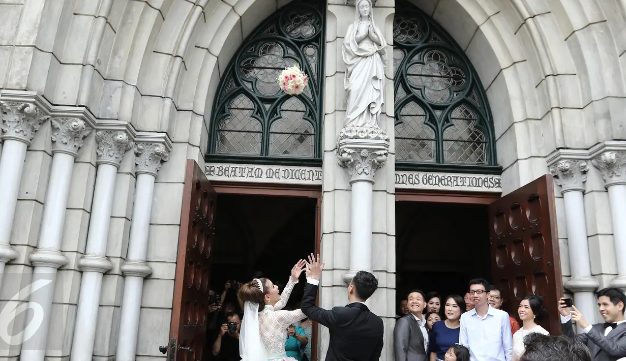 Aktris Olga Lydia dan Aris Utama melempar bunga seusai menjalankan sakramen pernikahan di Gereja Katedral, Jakarta, Jumat (21/4). Aktris Olga Lydia dan Aris Utama menjalankan sakramen pernikahan. (Liputan6.com/Herman Zakharia)