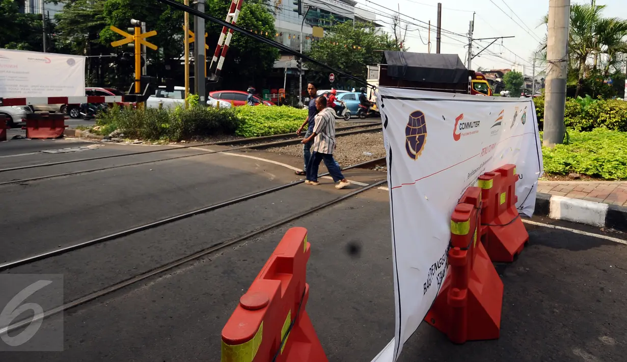 Warga melintasi perlintasan KA Pejompongan 1 yang ditutup sementara, Jakarta, Rabu (12/4). Perlintasan KA Pejompongan 1 akan ditutup permanen pada 5 Mei mendatang. (Liputan6.com/Helmi Fithriansyah)