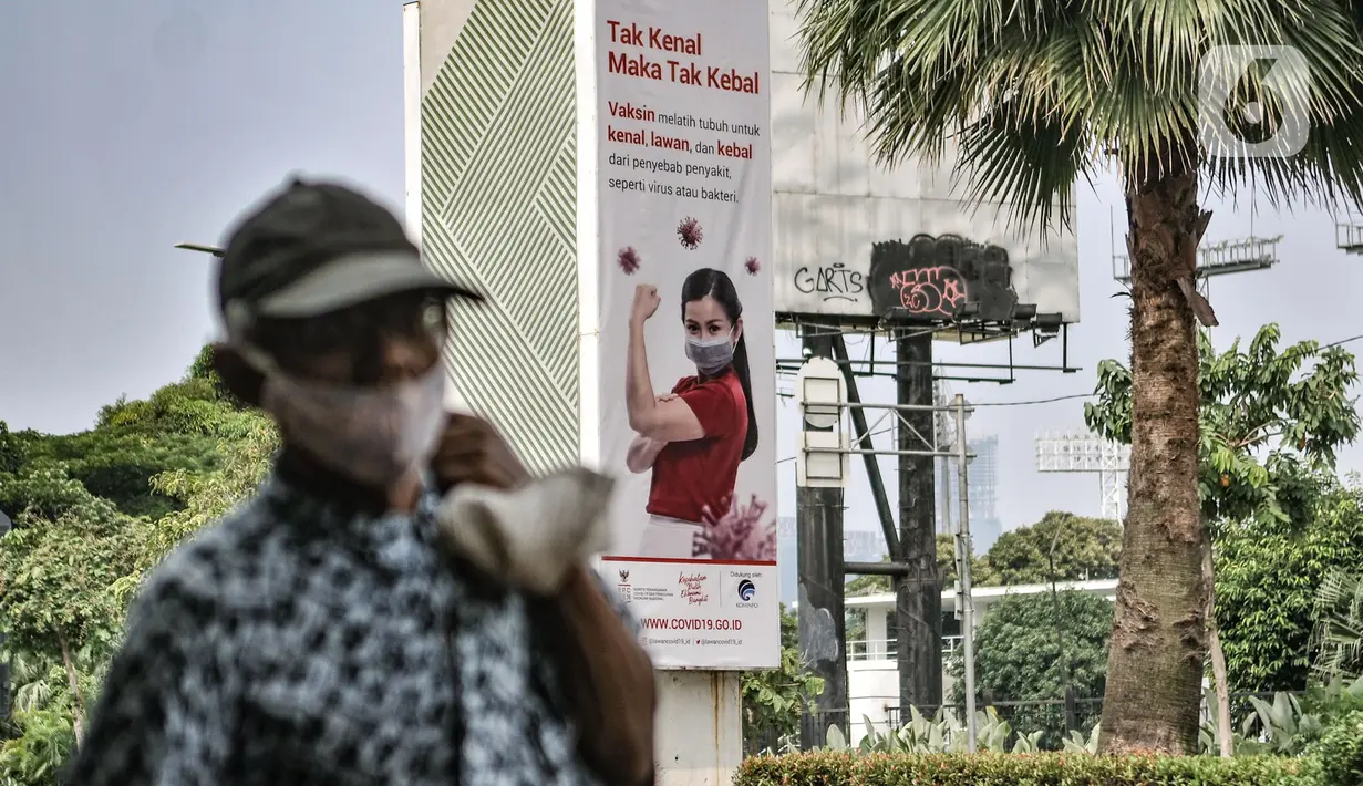 Warga melintas di dekat papan reklame sosialisasi vaksin Covid- di tiang pancang proyek monorel, Senayan, Jakarta, Selasa (17/11/2020). Papan reklame bertuliskan "Tak Kenal Maka Tak Kebal" mengimbau agar masyarakat tidak perlu takut terhadap suntikan Vaksin Covid-19. (merdeka.com/Iqbal S Nugroho)