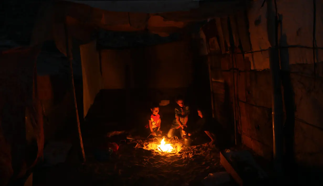 Warga Palestina duduk mengitari api unggun di luar rumah saat pemadaman listrik terjadi di Kota Khan Younis, Jalur Gaza selatan, pada 18 Agustus 2020. Satu-satunya pembangkit listrik di Jalur Gaza telah sepenuhnya berhenti beroperasi akibat kehabisan bahan bakar. (Xinhua/Yasser Qudih)