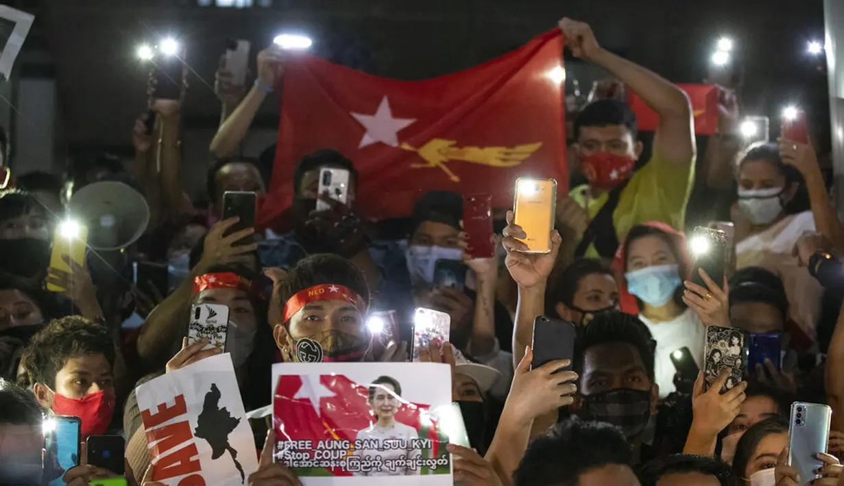 Warga Myanmar yang tinggal di Thailand memegang foto pemimpin Myanmar Aung San Suu Kyi dan menyalakan lampu ponsel saat protes di depan Kedutaan Besar Myanmar di Bangkok, Thailand, Kamis (4/2/2021). Warga memprotes kudeta militer yang terjadi Myanmar. (AP Photo/Sakchai Lalit)