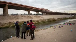 Sekelompok kecil imigran mendiskusikan apakah akan menyeberangi Rio Grande atau tidak dari Ciudad Juarez, Meksiko, dan menyerah kepada Patroli Perbatasan di El Paso, Texas, 18 Desember 2022. Kota-kota perbatasan Texas bersiap menghadapi lonjakan sebanyak 5.000 imigran baru setiap hari yang melintasi perbatasan AS-Meksiko karena pembatasan imigrasi era pandemi berakhir minggu ini. (AP Photo/Andres Leighton)