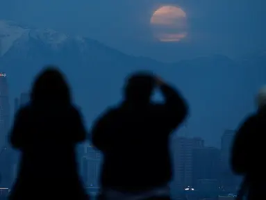 Orang-orang menyaksikan fenomena supermoon atau bulan super dengan latar belakang pusat kota Los Angeles dari Kenneth Hahn Park, Minggu (20/1). Supermoon akhir pekan ini adalah yang pertama terjadi pada tahun 2019 ini. (AP/Ringo H.W. Chiu)