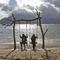 Dua wanita bermain ayunan saat menikmati Pantai Mutiara di Trenggalek, Jawa Timur, Sabtu (7/9/2019). Pantai Mutiara salah satu tujuan wisata yang sedang dikembangkan kabupaten Trenggalek. (Liputan6.com/Herman Zakharia)