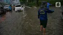 Petugas mengatur kelancaran lalu lintas saat air menggenangi ruas Jalan Gatot Subroto, Jakarta, Kamis (18/2/2021). Hujan deras yang mengguyur wilayah Jakarta menyebabkan terjadinya genangan di beberapa ruas jalan, meski begitu sejauh ini kendaraan masih dapat melintas. (Liputan6.com/Faizal Fanani)